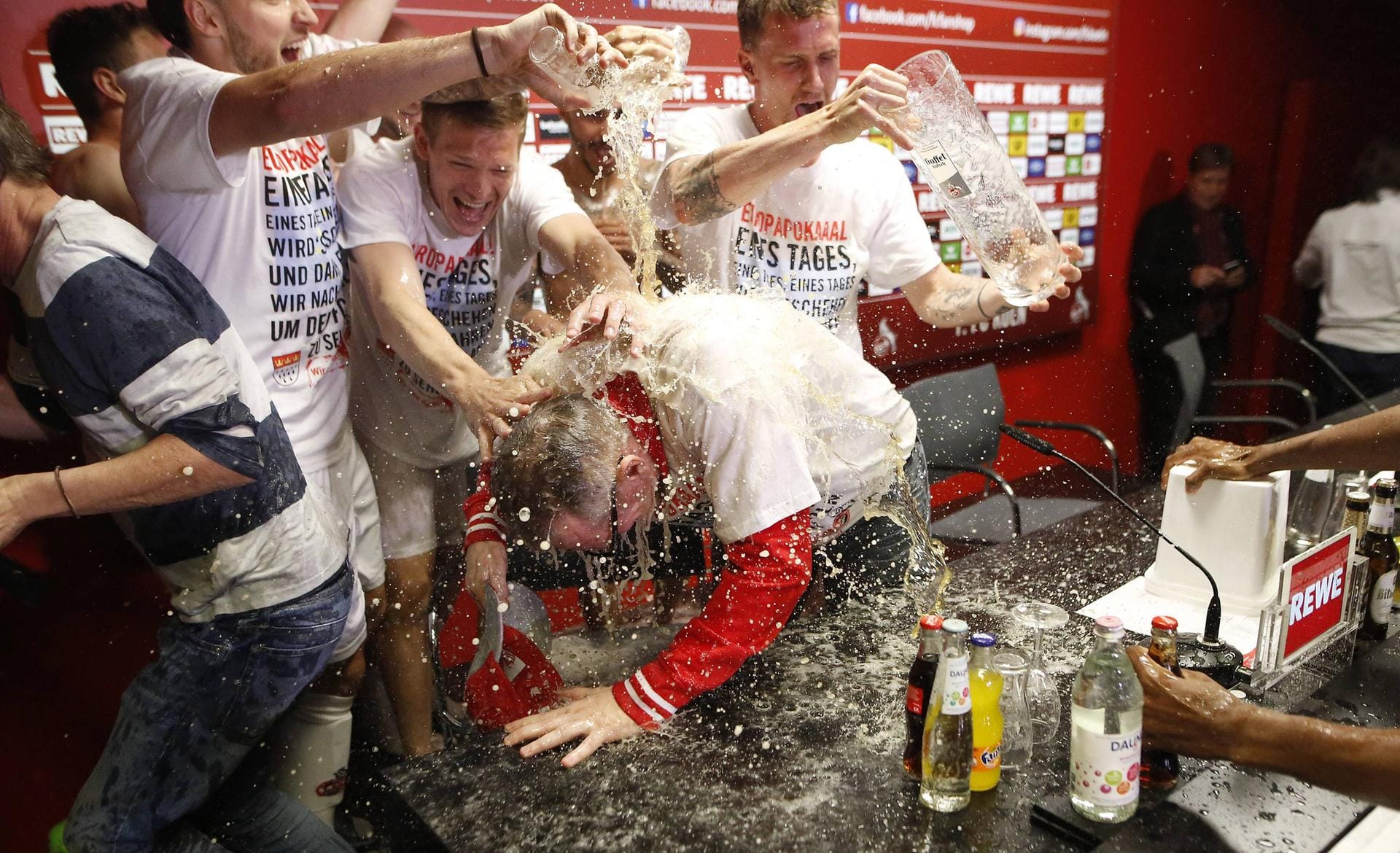 Die Köln-Profis bedanken sich bei Trainer Peter Stöger mit einer Bierdusche – während der Pressekonferenz.