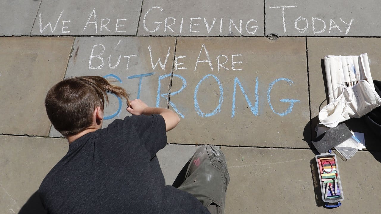 Ein junger Künstler schreibt auf dem St Ann's Square in Manchester den Spruch "We are grieving today but we are strong" (Heute trauern wir, aber wir sind stark).