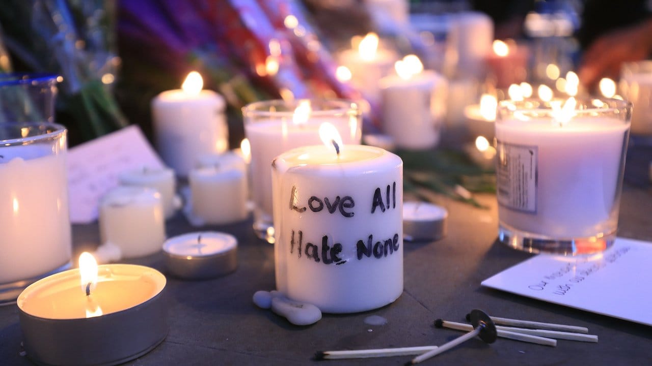 Auf einer Gedenkkerze steht: Liebe alle, hasse niemanden.
