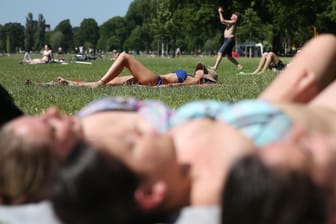 Im Düsseldorfer Rheinpark genießen die Menschen das sommerliche Wetter.