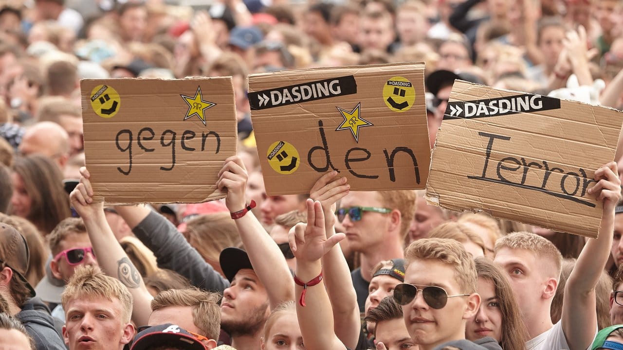 Besucher des Musikfestivals "Rock am Ring" halten in Nürburg vor der Bühne Schilder gegen Terrorismus hoch.