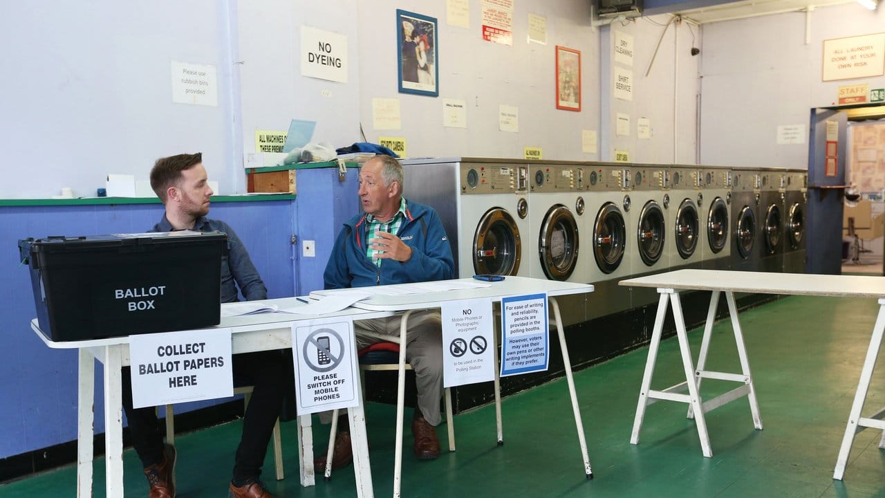 Zwei Wahlhelfer sitzen in Oxford in einem Waschsalon, in dem ein Wahllokal eingerichtet wurde.