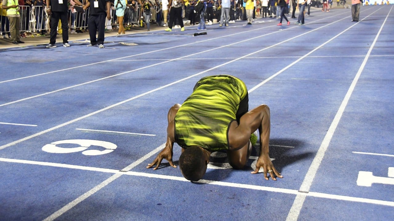 Usain Bolt küsst nach seinem Sieg beim "Racers Grand Prix" zum Abschied die Ziellinie der Tartanbahn in Kingston.