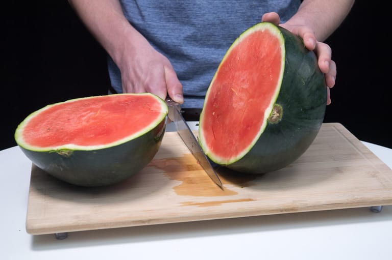 Die Messerklinge nach unten durchdrücken, sodass die Melone in zwei Hälften geteilt wird.