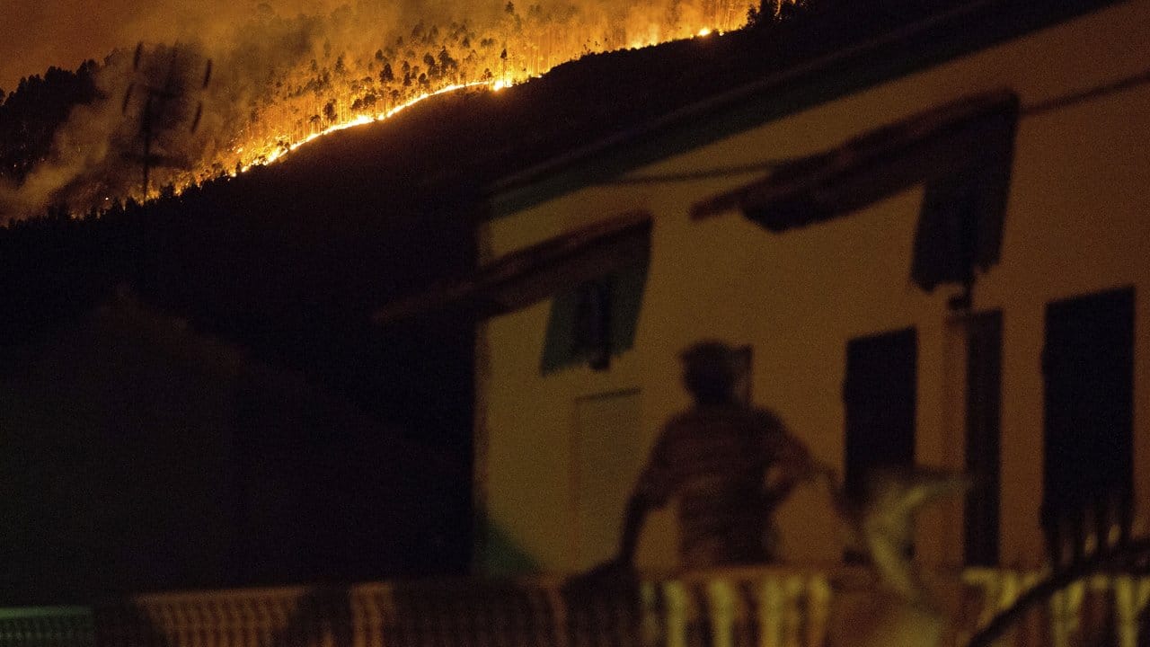 Ein Mann beobachtet in Avelar einen Waldbrand auf einem Hügel nahe der Stadt.