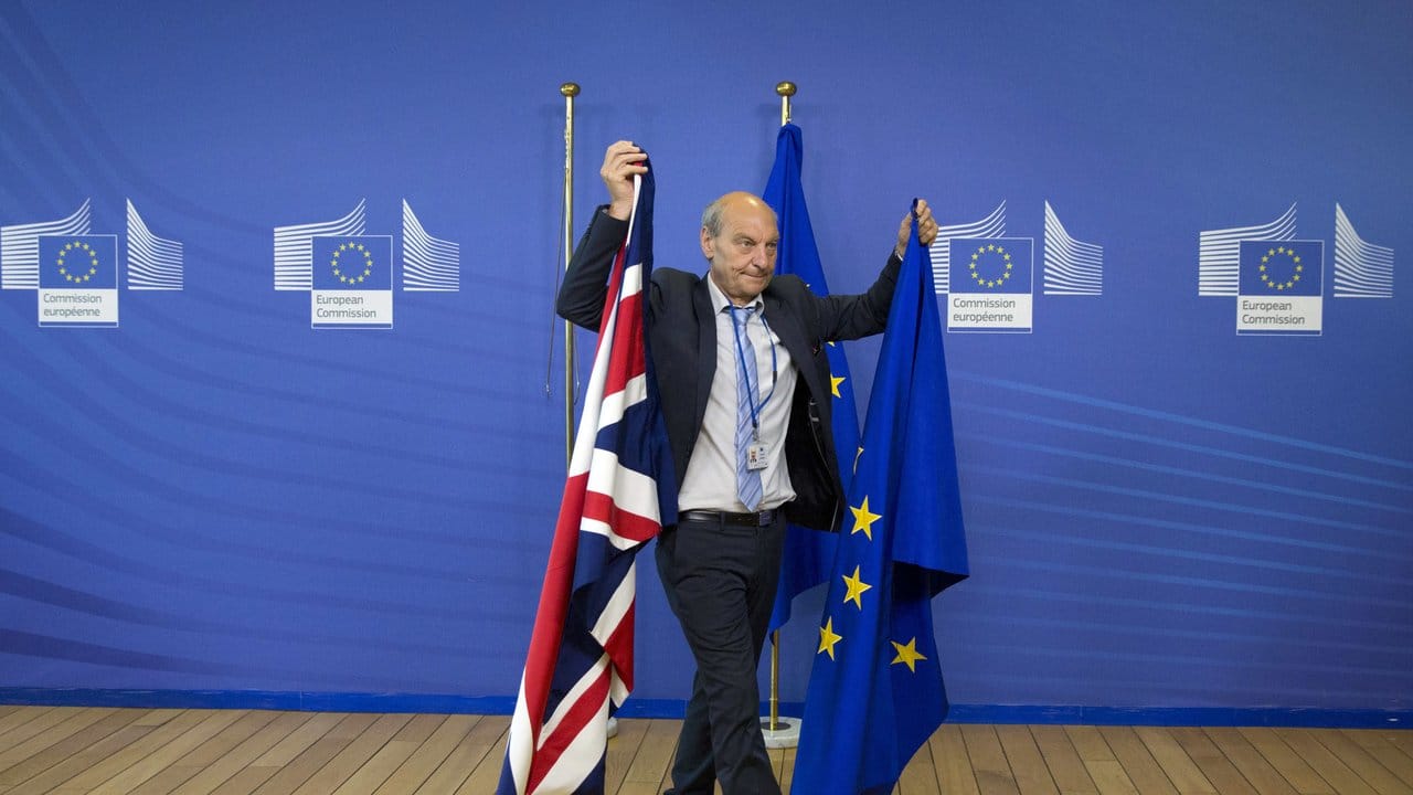 Ein Mitglied des Protokolls tauscht in Brüssel eine EU-Flagge gegen eine britische Flagge aus.
