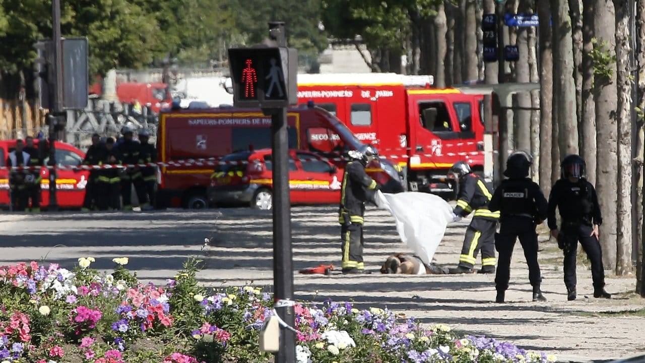 Rettungskräfte bedecken auf den Champs-Elysees in Paris einen am Boden liegenden Mann mit einem Tuch.