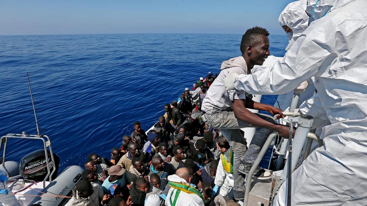 Gerettet: Auf dem Mittelmeer vor Italien besteigen Migranten ein Schiff der Guardia di Finanza.