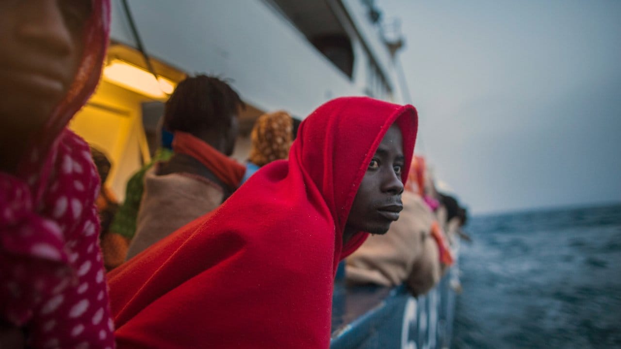 Gerettete afrikanische Migranten schauen von einem Rettungsschiff der spanischen Hilfsorganisation Proactiva Open Arms auf das Mittelmeer.