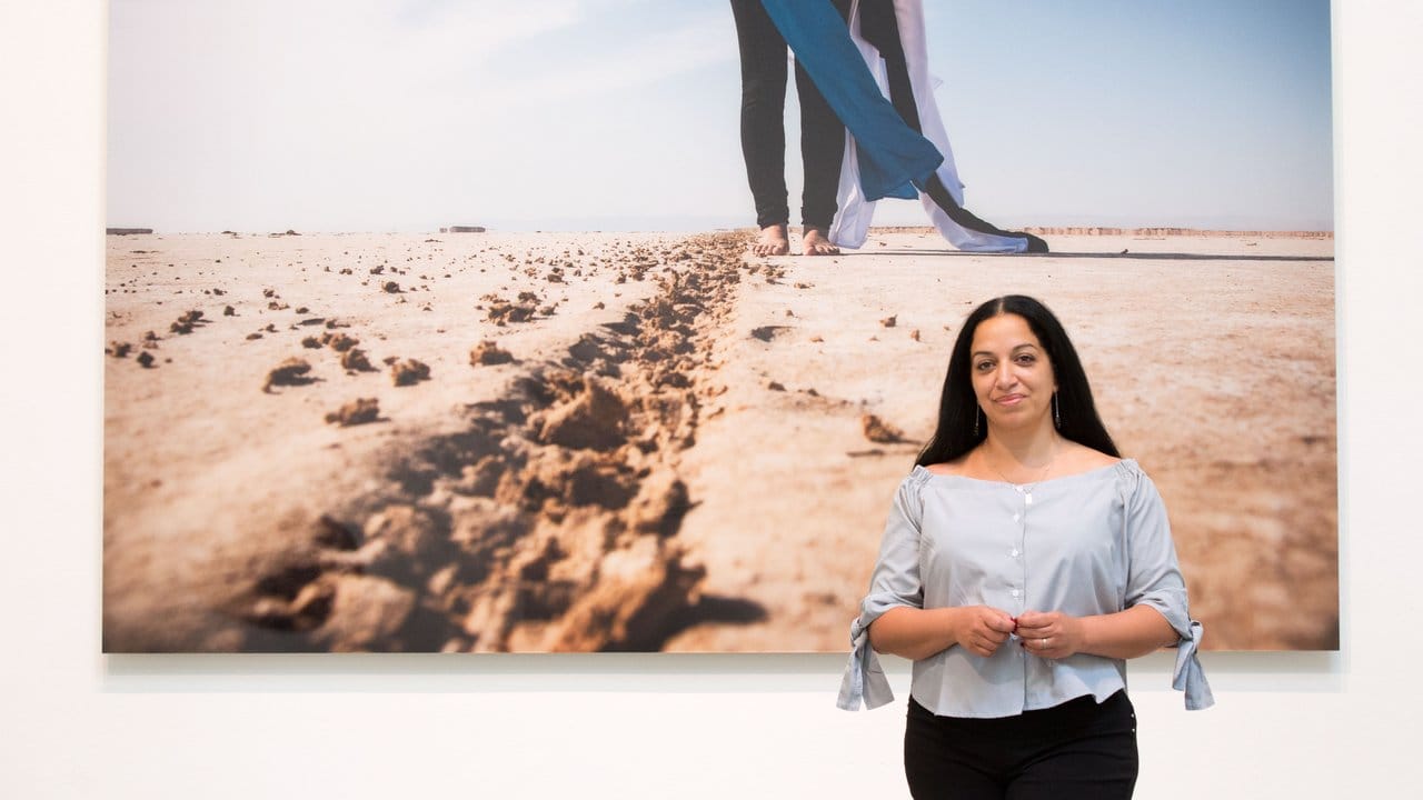 Die Künstlerin Sama Alshaibi vor ihrer Fotografie mit dem Titel "Al-Tariqah (The Path)" von 2014.