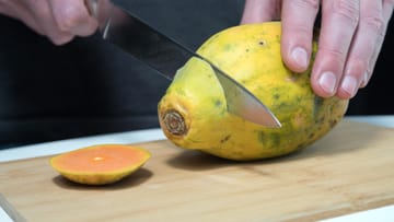 1. Schritt: Legen Sie die Papaya auf das Schneidbrett und schneiden Sie sie an beiden Enden gerade ab. Die Messerklinge sollte länger als die Papaya sein.