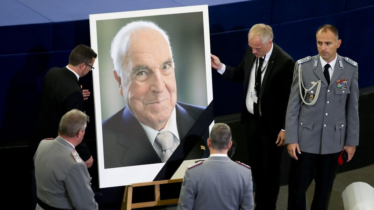 Saaldiener stellen vor dem europäischen Trauerakt für Helmut Kohl im EU-Parlament in Straßburg ein Porträt des Altkanzlers auf.