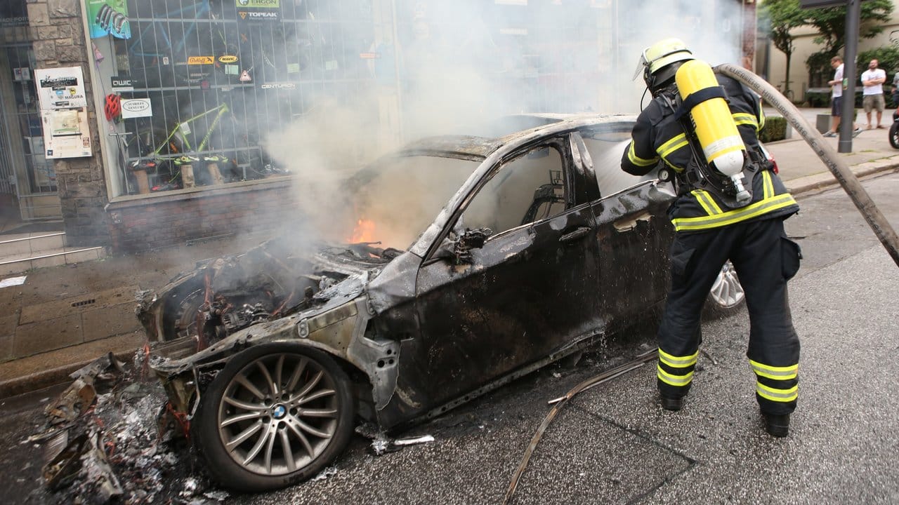 Ein Feuerwehrmann löscht in Altona ein brennendes Auto. Ein Feuerwehrmann löscht in Altona ein brennendes Auto.