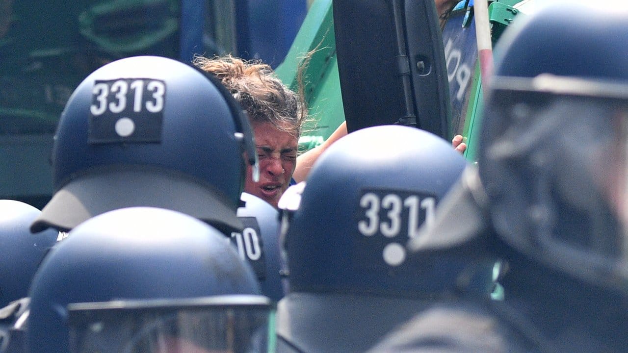 Umringt: Einer Frau, die auf ein Polizeifahrzeug geklettert war, ist deutlich anzusehen, dass Pfefferspray zum Einsatz kam. Umringt: Einer Frau, die auf ein Polizeifahrzeug geklettert war, ist deutlich anzusehen, dass Pfefferspray zum Einsatz kam.