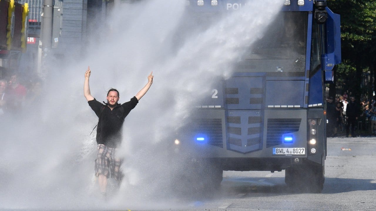 Ein Demonstrant stellt sich im Bereich der Reeperbahn in Hamburg einem Wasserwerfer entgegen. Ein Demonstrant stellt sich im Bereich der Reeperbahn in Hamburg einem Wasserwerfer entgegen.