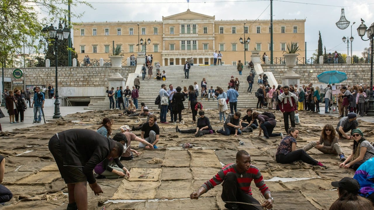 Auf dem Syntagma-Platz in Athen nähen bei der Performance "Check Point - Prosfygika" des Künstlers Ibrahim Mahama aus Ghana junge Menschen Jute-Säcke zusammen.