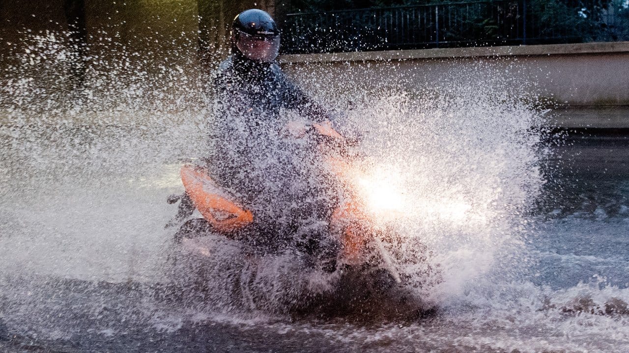 Ein Motorrollerfahrer bei einem schweren Unwetter mit Starkregen über eine überflutete Straße in der Region Hannover.