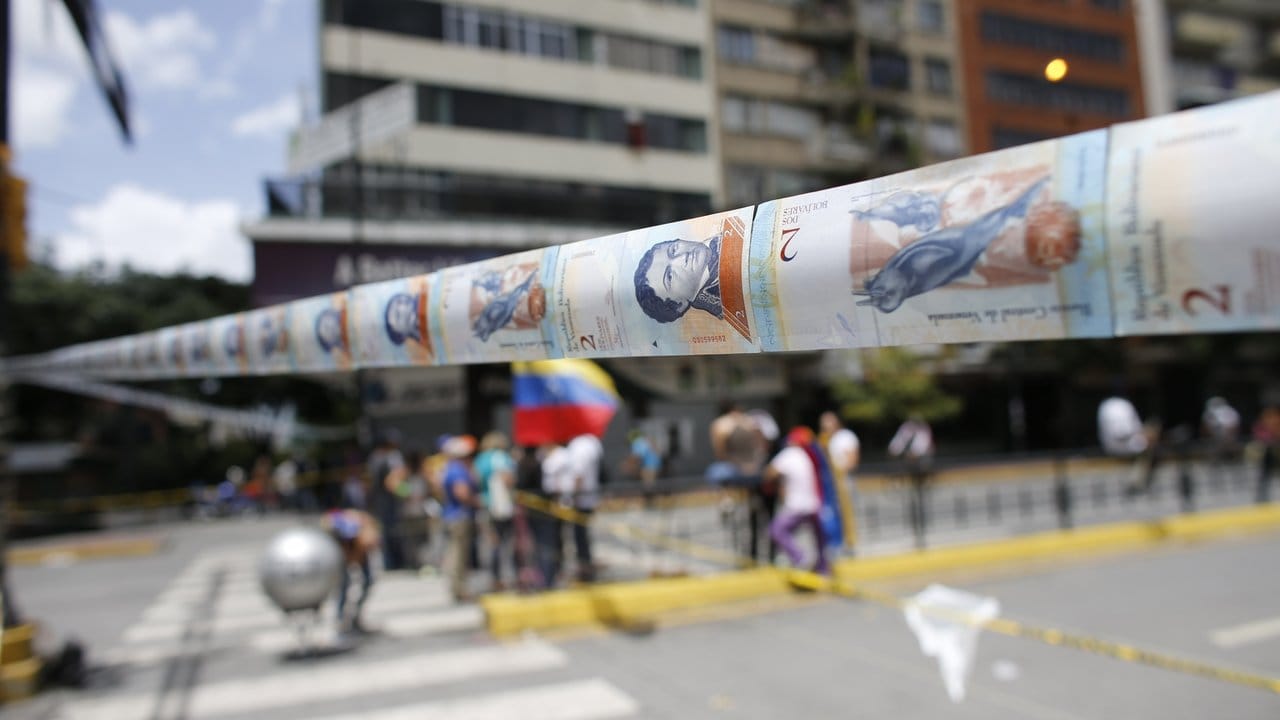 Mit abgewerteten Scheine haben Demonstranten eine Straße in Caracas gesperrt.