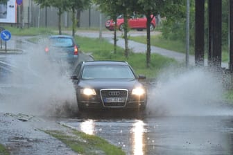 Autos fahren durch vom Regen überspülte Straßen in Oranienburg (Brandenburg).