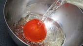 2. Die Tomate in eine Schüssel legen und mit kochendem Wasser übergießen.