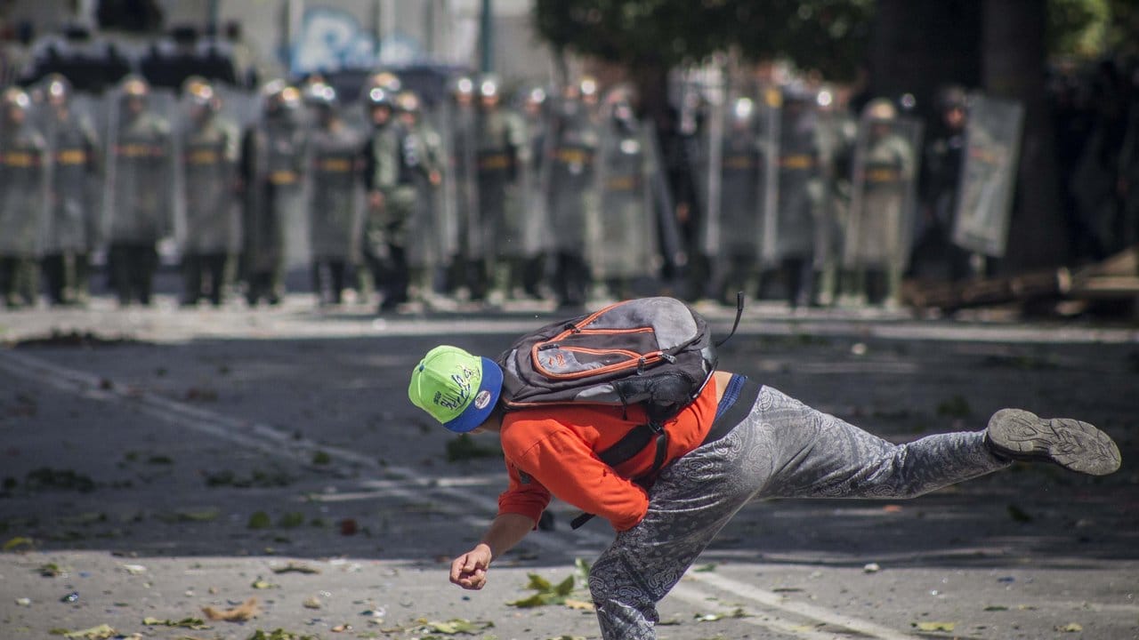 Ein Demonstrant wirft in Caracas Steine auf Soldaten.