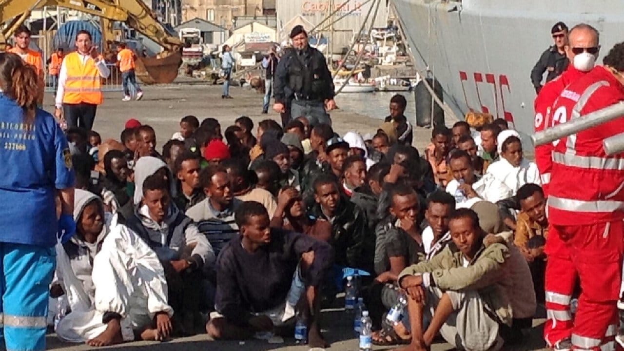 Eine Gruppe von Flüchtlingen wartet im Hafen von Catania, Sizilien (Italien), nachdem sie ein italienisches Marineschiff verlassen haben, das sie gerettet hat.
