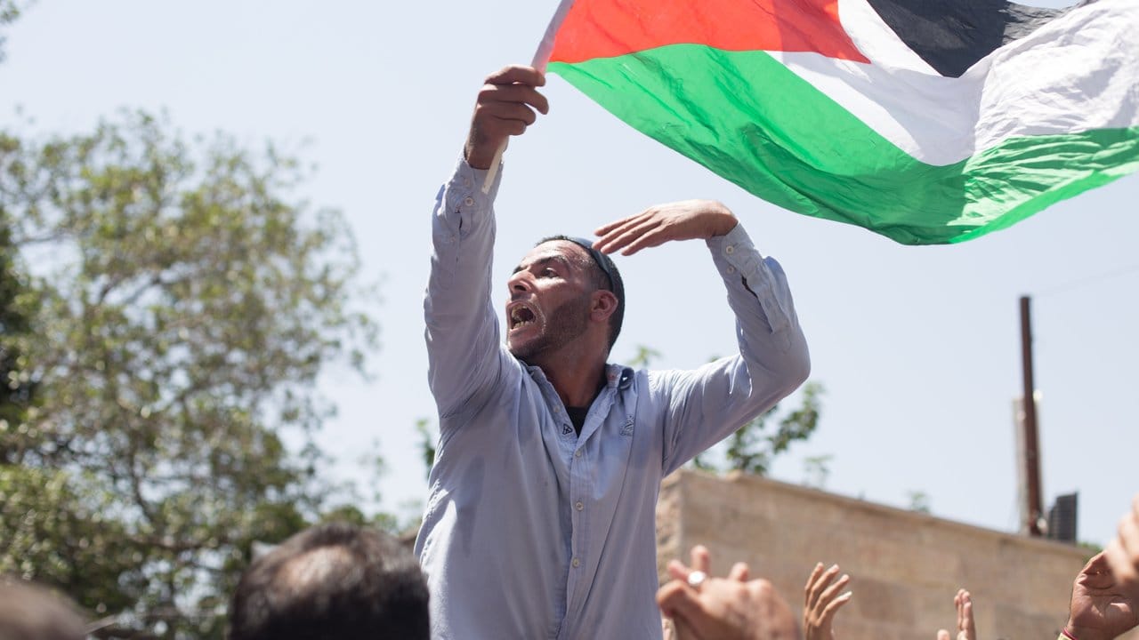 Ein Mann schwenkt in Jerusalem eine palästinensische Flagge.