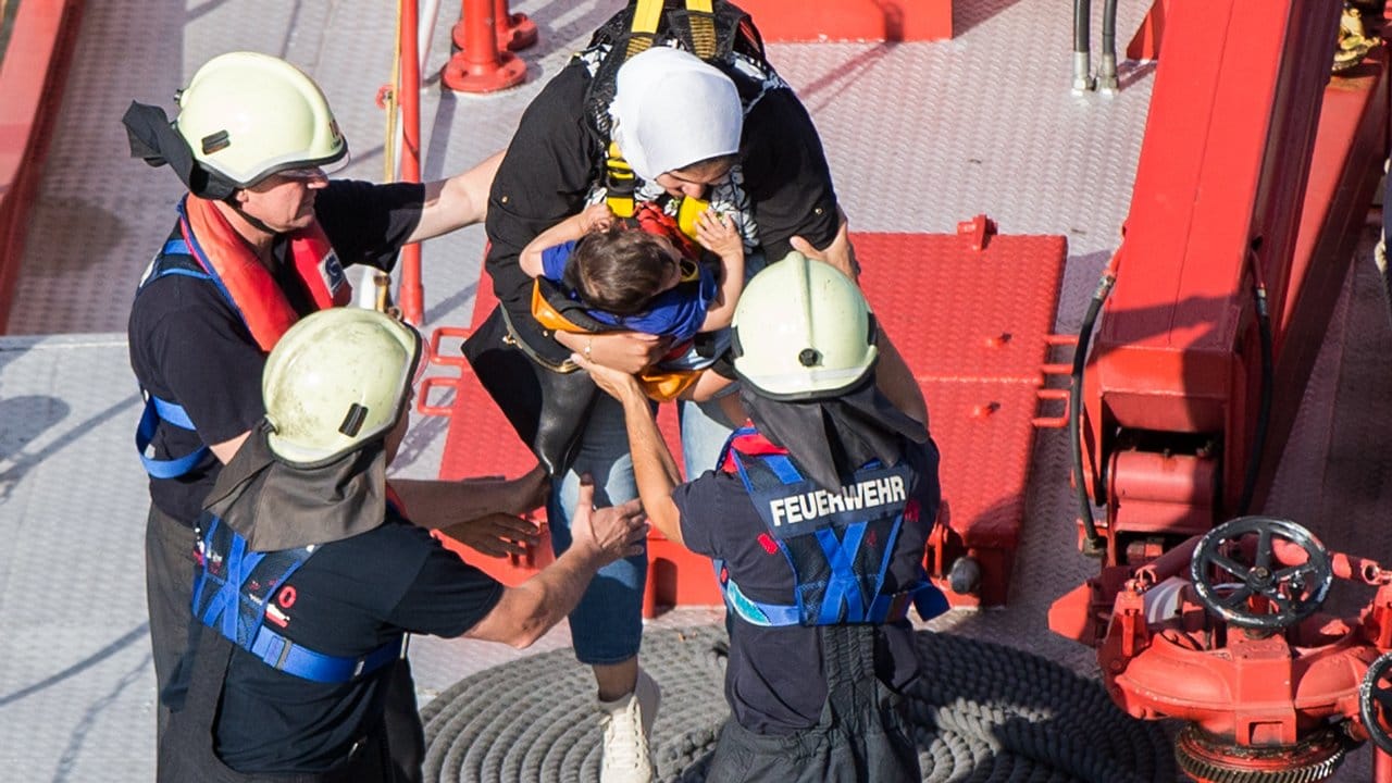 Eine Mutter mit ihrem Kind wird von Feuerwehrleuten versorgt. Eine Mutter mit ihrem Kind wird von Feuerwehrleuten versorgt.