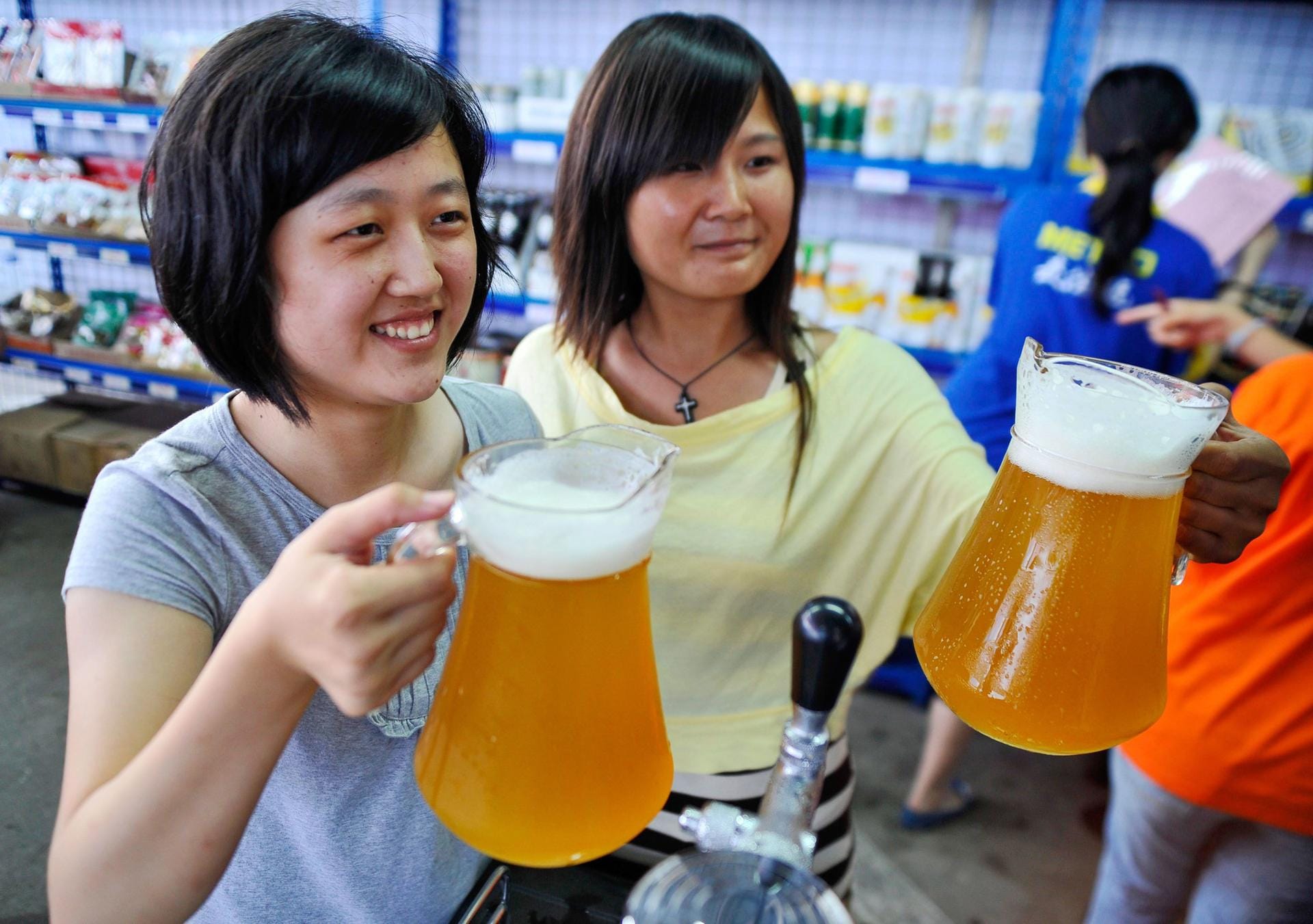 Zwei Chinesinnen probieren bei einem deutschen Bierfestival in der Stadt Qingdao Bier in Glaskrügen.