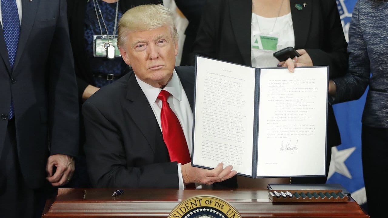 Januar 2017: US-Präsident Donald Trump hält ein Dekret für Maßnahmen zur Begrenzung der Einwanderung und dem Bau einer Grenzmauer zu Mexiko hoch. Januar 2017: US-Präsident Donald Trump hält ein Dekret für Maßnahmen zur Begrenzung der Einwanderung und dem Bau einer Grenzmauer zu Mexiko hoch.
