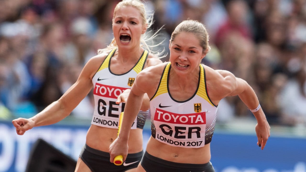 Gina Lückenkemper (l) und Rebekka Haase wechseln im Vorlauf der 4x100 Meter Staffel.