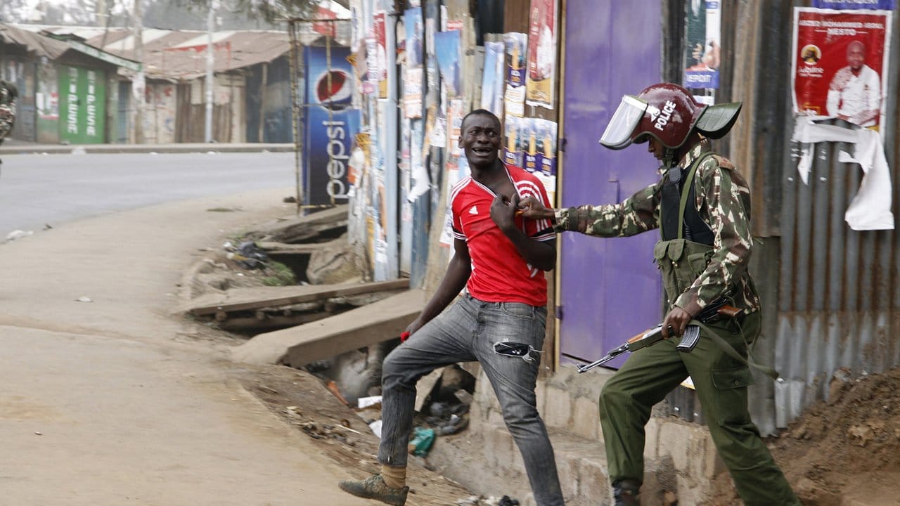 Ein Unterstützer des Oppositionsführers Odinga wird in einem Slum in Nairobi von einem Polizisten festgehalten. Ein Unterstützer des Oppositionsführers Odinga wird in einem Slum in Nairobi von einem Polizisten festgehalten.