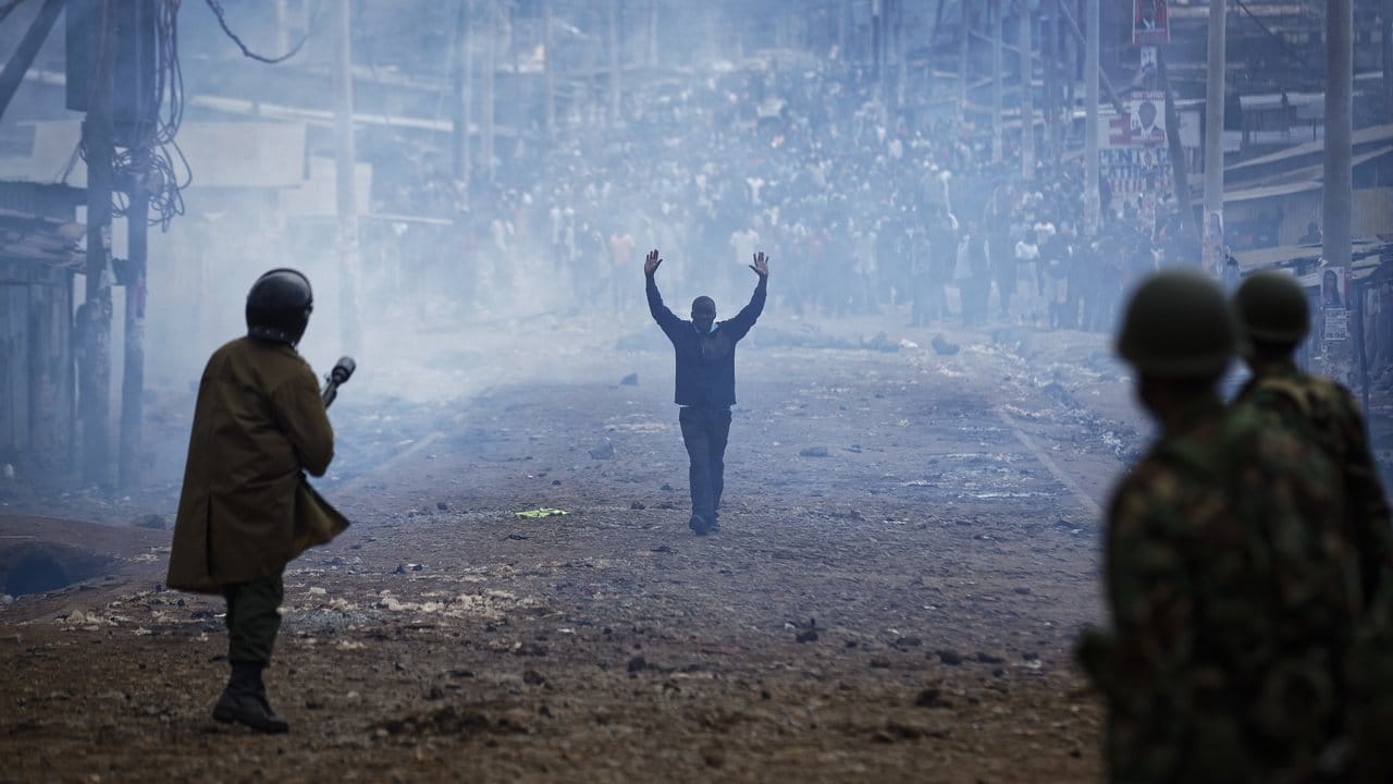 Ein Mann nähert sich mit erhobenen Armen in Nairobi einer Gruppe von Polizisten. Ein Mann nähert sich mit erhobenen Armen in Nairobi einer Gruppe von Polizisten.