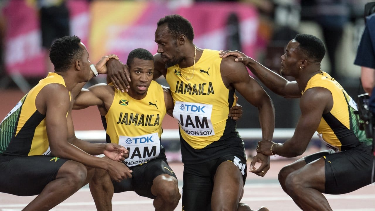 Bolts Teamkameraden stützen den großen Mann beim Aufstehen.