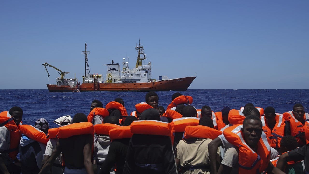 Flüchtlinge warten in einem überladenen Boot auf Helfer.