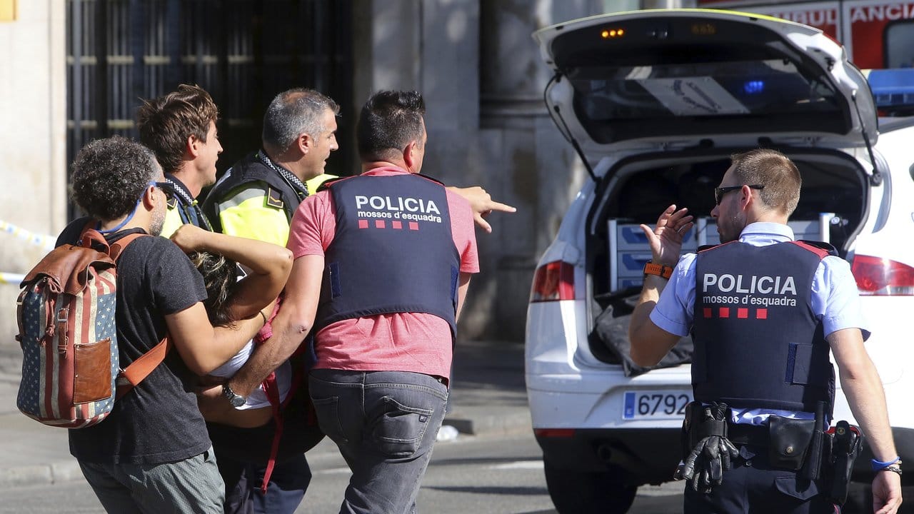 Polizisten und Sanitäter tragen eine verletzte Frau über die Straße.