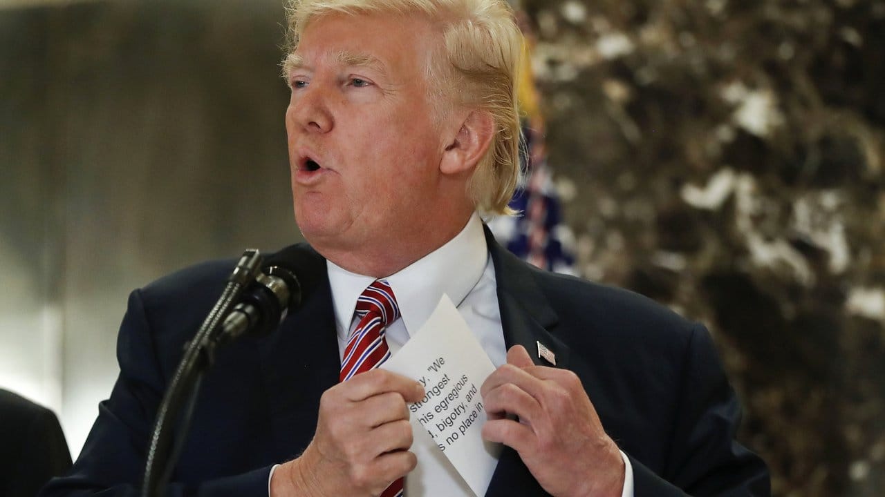 US-Präsident Trump greift während seiner Aufsehen erregenden Pressekonferenz nach einem Zettel mit Anmerkungen.