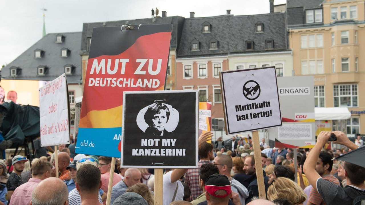 Protestler stehen während eines Wahlkampfauftritts von Bundeskanzlerin Merkel auf dem Marktplatz in Annaberg-Buchholz. Protestler stehen während eines Wahlkampfauftritts von Bundeskanzlerin Merkel auf dem Marktplatz in Annaberg-Buchholz.