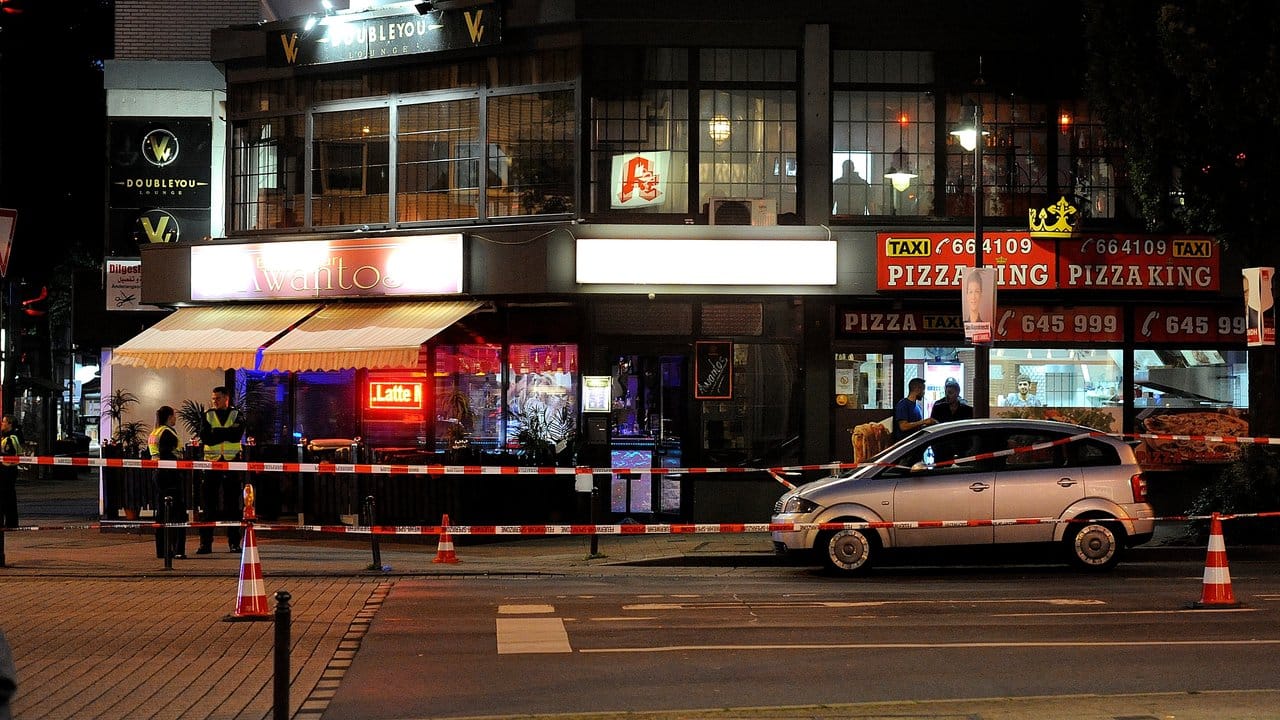 Polizisten stehen in einem mit Absperrband abgegrenzten Bereich vor einem Bistro in Wuppertal.