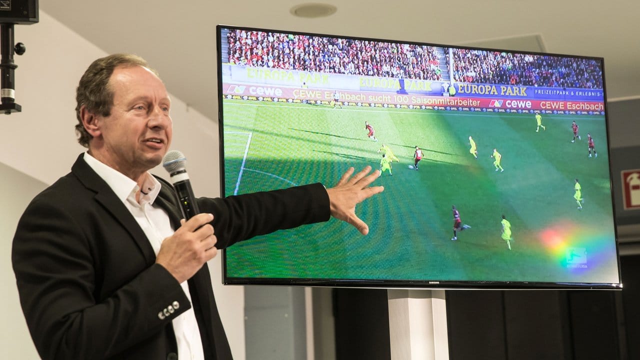 Hellmut Krug erläutert bei einer Pressekonferenz eine Spielszene auf einem Monitor.