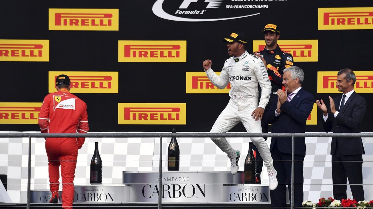 Während der Renn-Zweite Sebastian Vettel (r) noch das Podest erklimmt bejubelt Lewis Hamilton seinen Triumph. Während der Renn-Zweite Sebastian Vettel (r) noch das Podest erklimmt bejubelt Lewis Hamilton seinen Triumph.