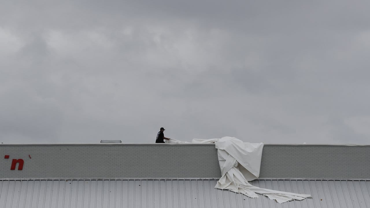 Ein Mann deckt ein vom Tropensturm "Harvey" beschädigtes Dach in Rockport provisorisch mit einer Plane ab. Ein Mann deckt ein vom Tropensturm "Harvey" beschädigtes Dach in Rockport provisorisch mit einer Plane ab.