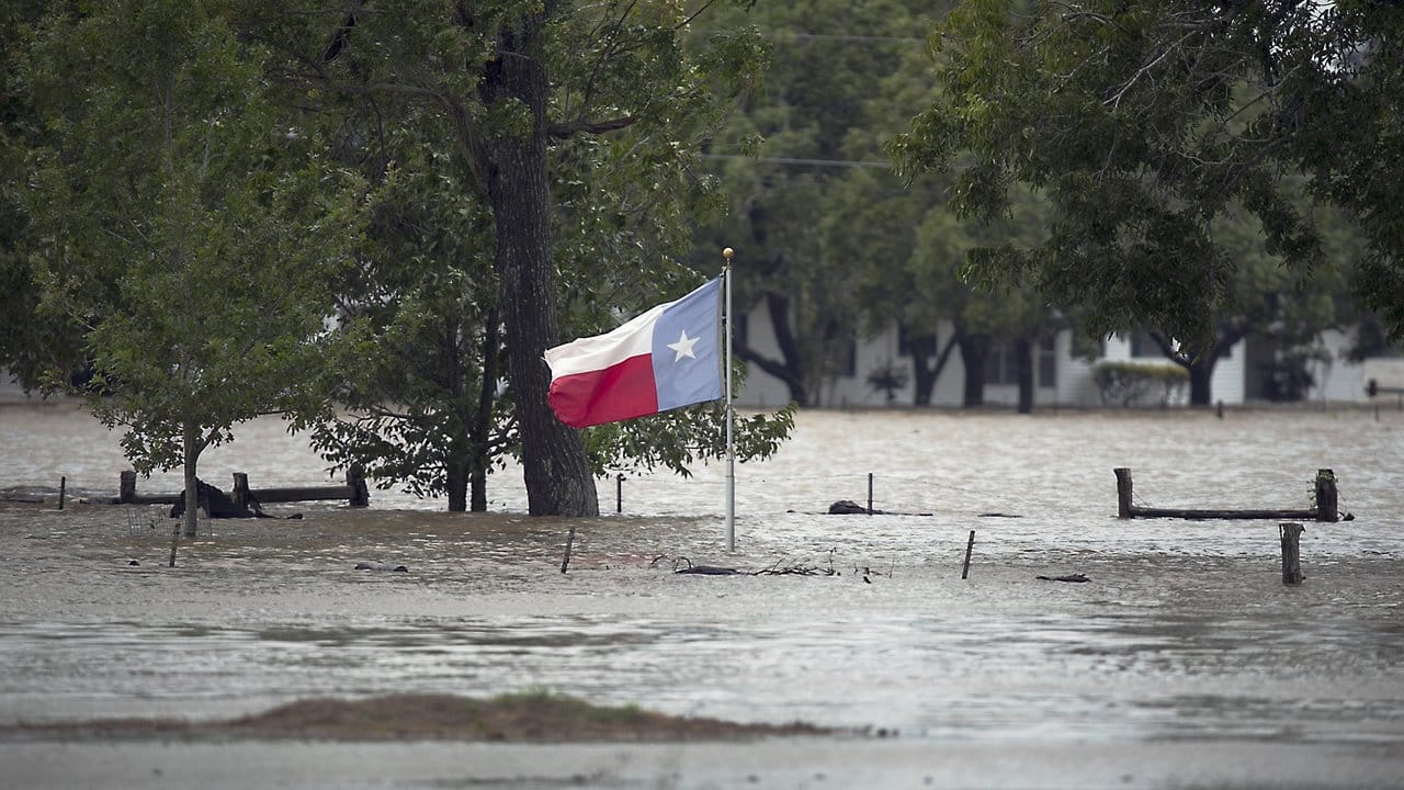 Eine texanische Flagge weht im texanischen La Grange an einem von Flutwasser umgebenen Fahnenmast. Eine texanische Flagge weht im texanischen La Grange an einem von Flutwasser umgebenen Fahnenmast.