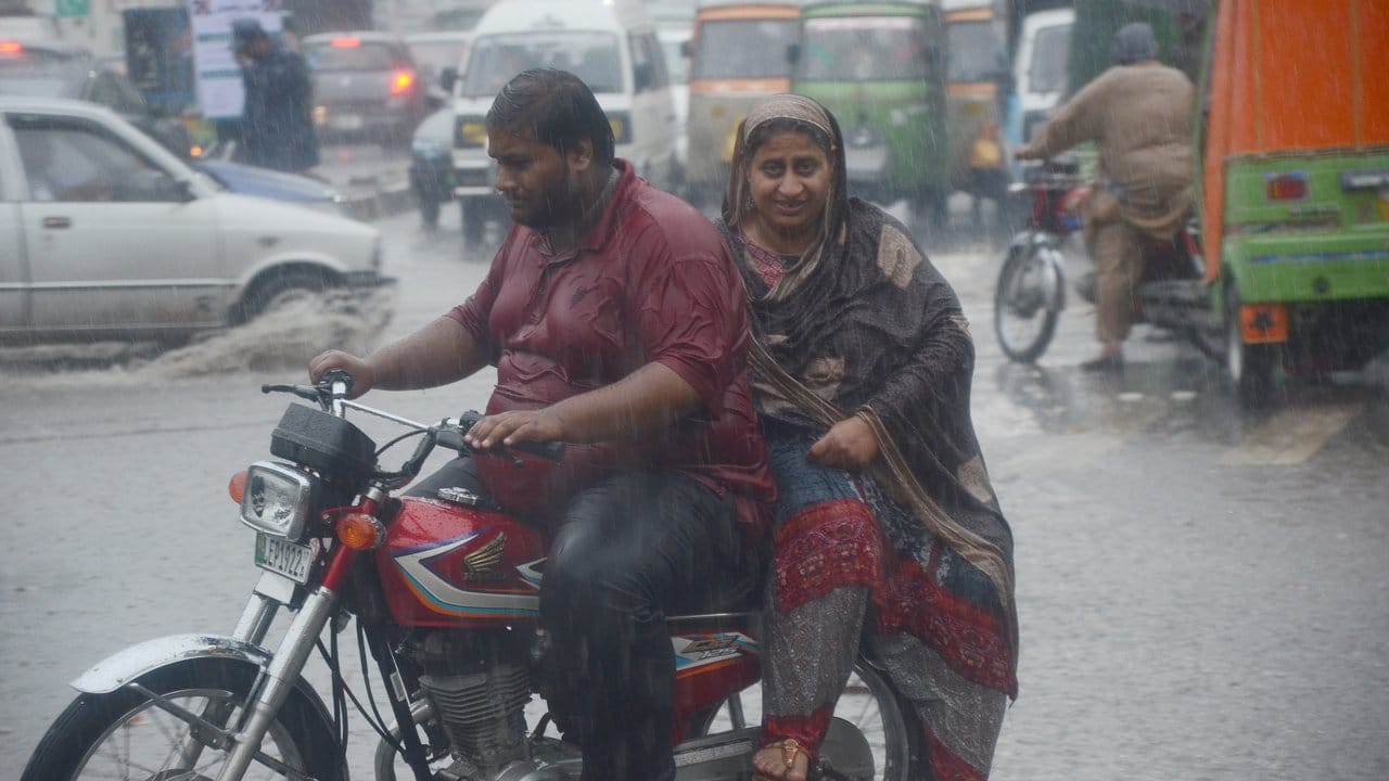 Ein Paar fährt über eine überschwemmte Straße in Lahore, Pakistan.
