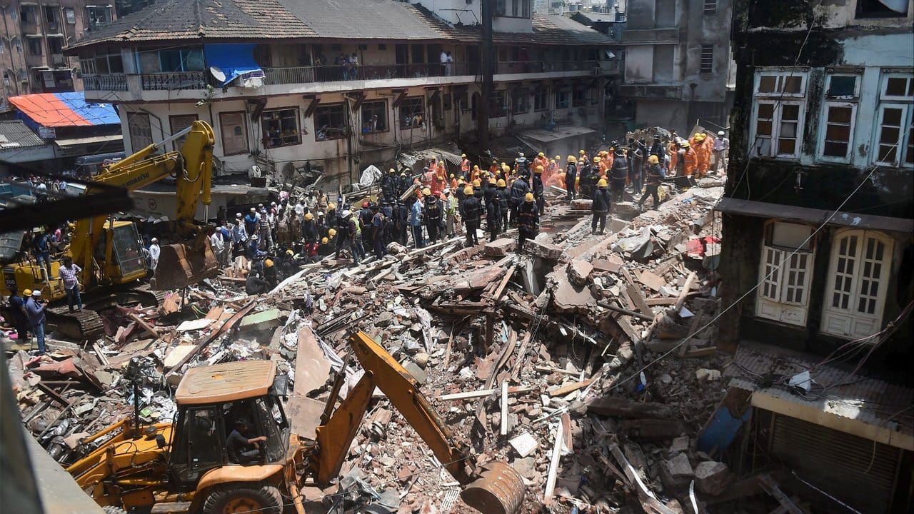 Feuerwehrmänner und Mitglieder einer Spezialeinheit arbeiten an den Trümmern eines eingestürzten Hauses in Mumbai.