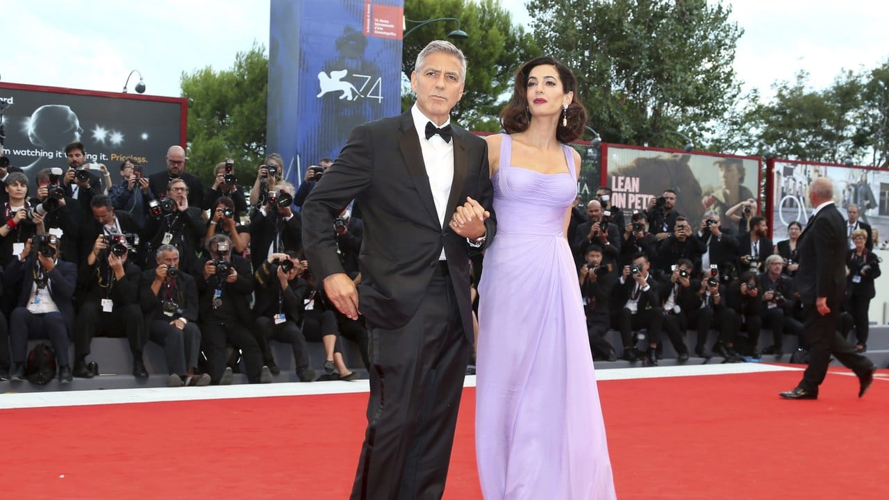 George Clooney trägt einen Tuxedo von Armani und seine Frau Amal hat sich für ein Outfit von Atelier Versace entschieden. George Clooney trägt einen Tuxedo von Armani und seine Frau Amal hat sich für ein Outfit von Atelier Versace entschieden.