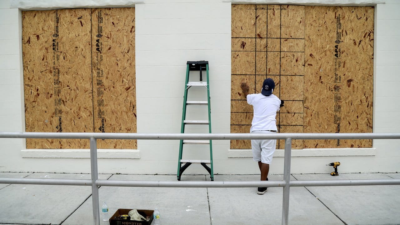 Pedro Gabriel sichert in Lake Worth (Florida, USA) die Fenster seines Antikgeschäftes mit Holzplatten.