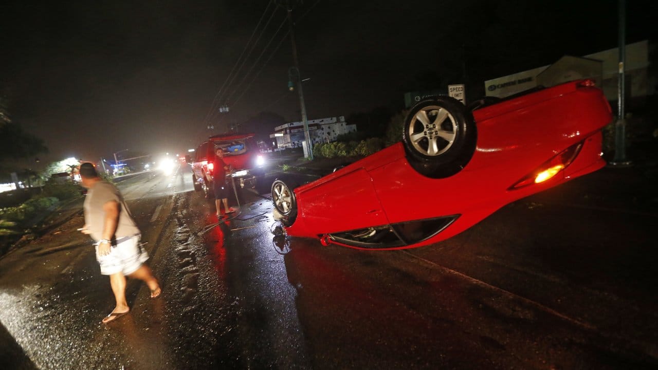 Menschen stehen in Cape Coral, Florida, neben einem umgeworfenen Fahrzeug. Menschen stehen in Cape Coral, Florida, neben einem umgeworfenen Fahrzeug.