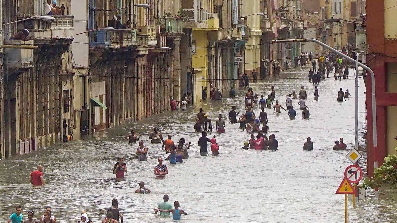 Kuba unter Wasser: Menschen waten in Havanna über eine überflutete Straße. Kuba unter Wasser: Menschen waten in Havanna über eine überflutete Straße.