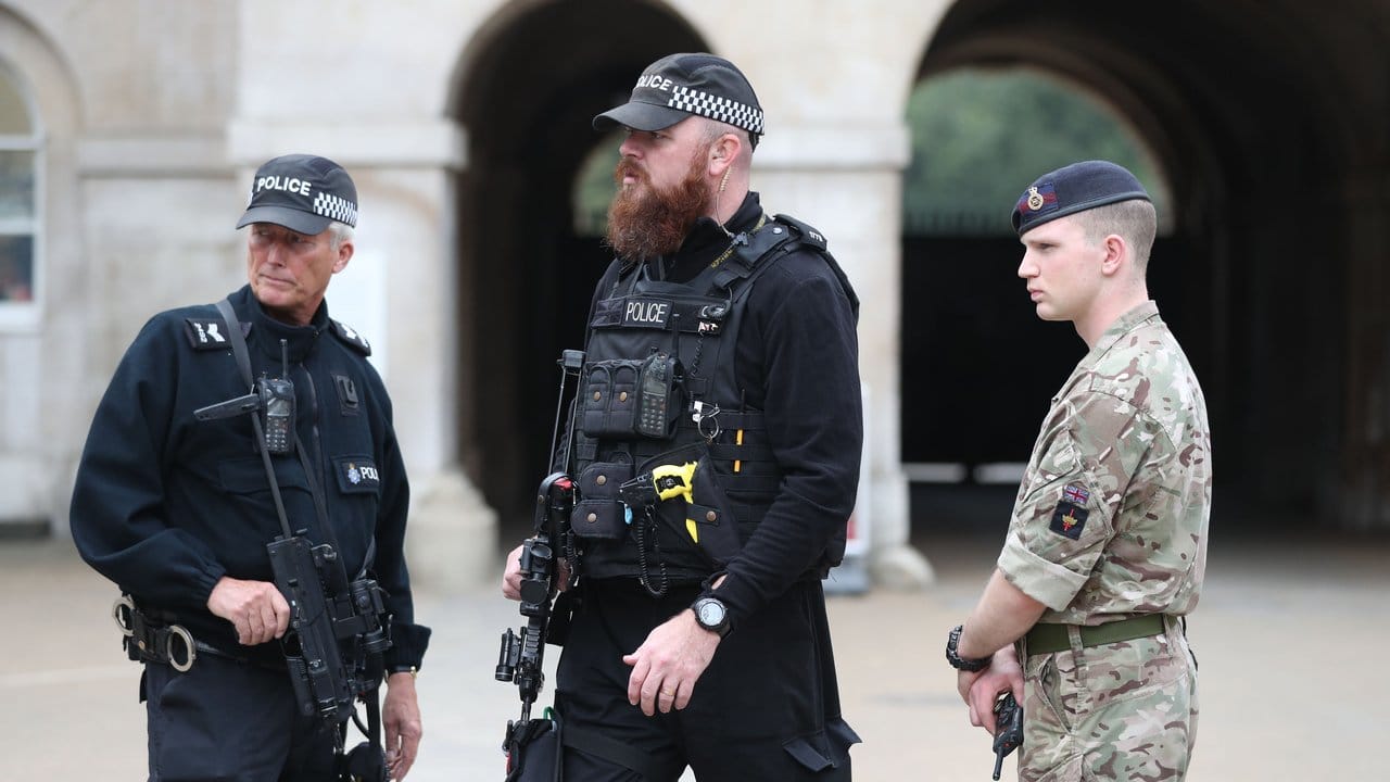 Bewaffnete Polizisten und ein Soldat sichern den Eingang zu Horse Guards in Whitehall in London. Bewaffnete Polizisten und ein Soldat sichern den Eingang zu Horse Guards in Whitehall in London.